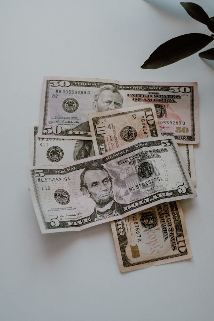 Close-up of various US dollar bills including  and 0 notes on a white surface.