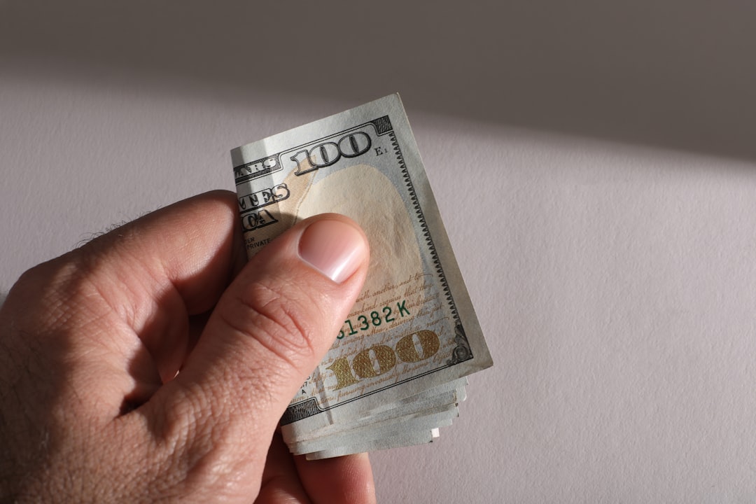 hand-holding-a-stack-of-us-hundred-dollar-bills-sfbv4yzclvy
